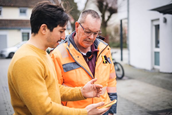 ein Mitarbeiter von vialytics erklärt einem Mann das system zur Straßeninstandhaltung 