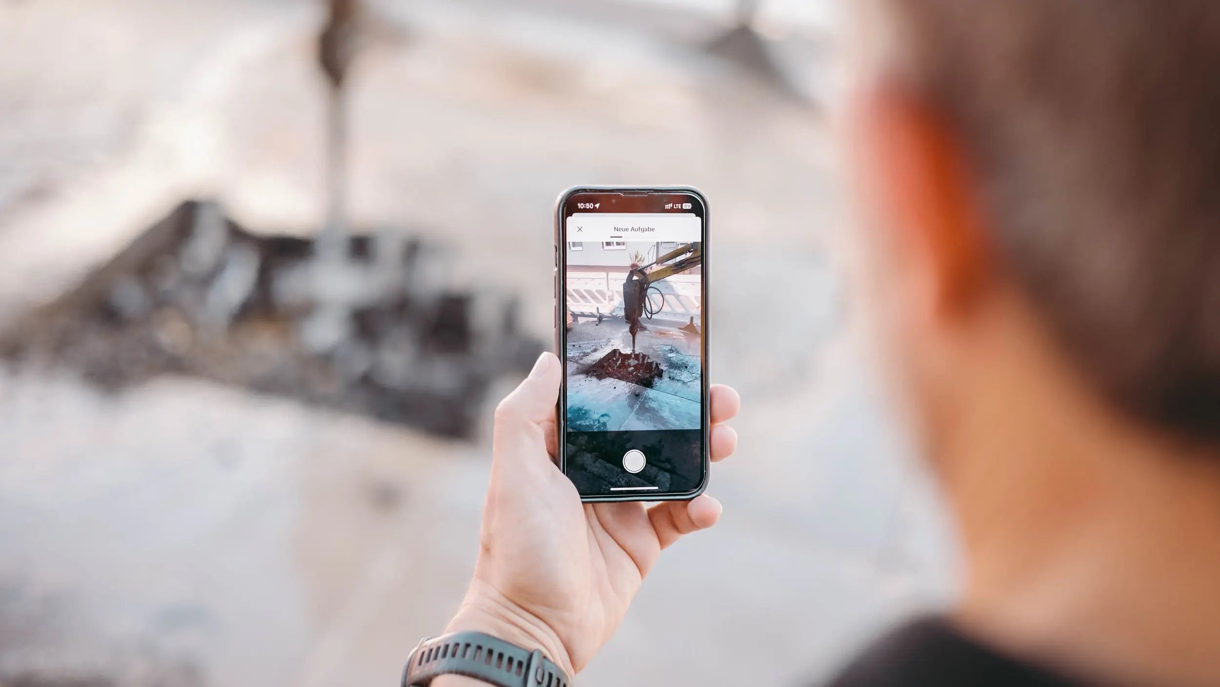 Ein Mann mit einem iPhone in der Hand fotografiert ein Loch in der Straße