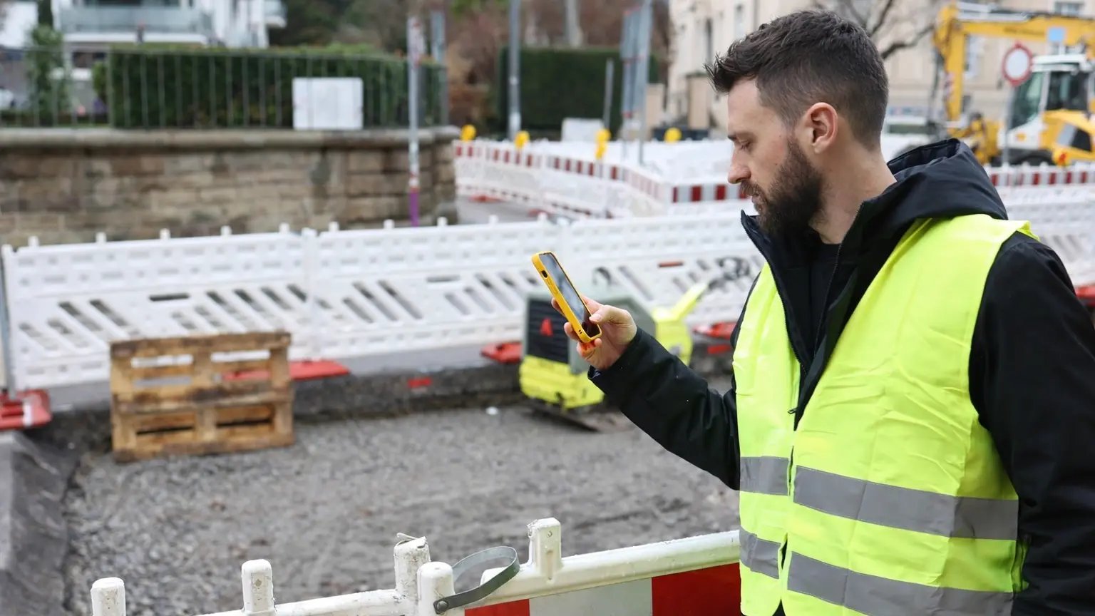 Mitarbeiter im Außendienst erfasst Gewährleistungsmängel auf einer Baustelle mit dem Smartphone