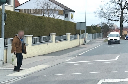Mann geht über eine Straße, sein Gesicht und das Kennzeichen eines Autos im Hintergrund sind DGSVO-konform verpixelt