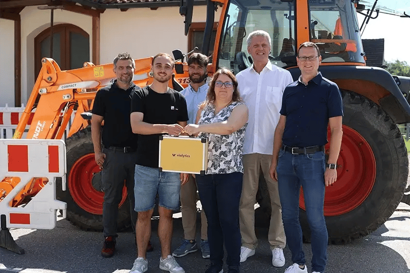 6 Personen stehen in Markt Biberbach vor einem Traktor. Sie präsentieren stolz den vialytics-Koffer.