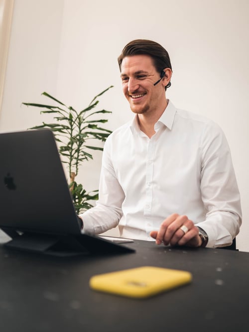 Unser Sales Mitarbeiter sitzt im Büro von vialytics vor einem Macbook und führt ein Kundengespräch