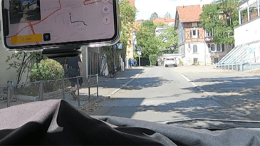 Ein iphone ist an einer Frontscheibe in einer Halterung befestigt und führt eine Zustandserfassung und -bewertung für Straßen durch