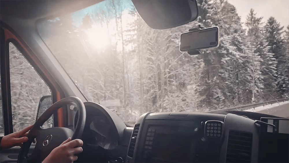 Bilck aus Auto in verschneitem Wald mit vialytics Phone in der Windschutzscheibe