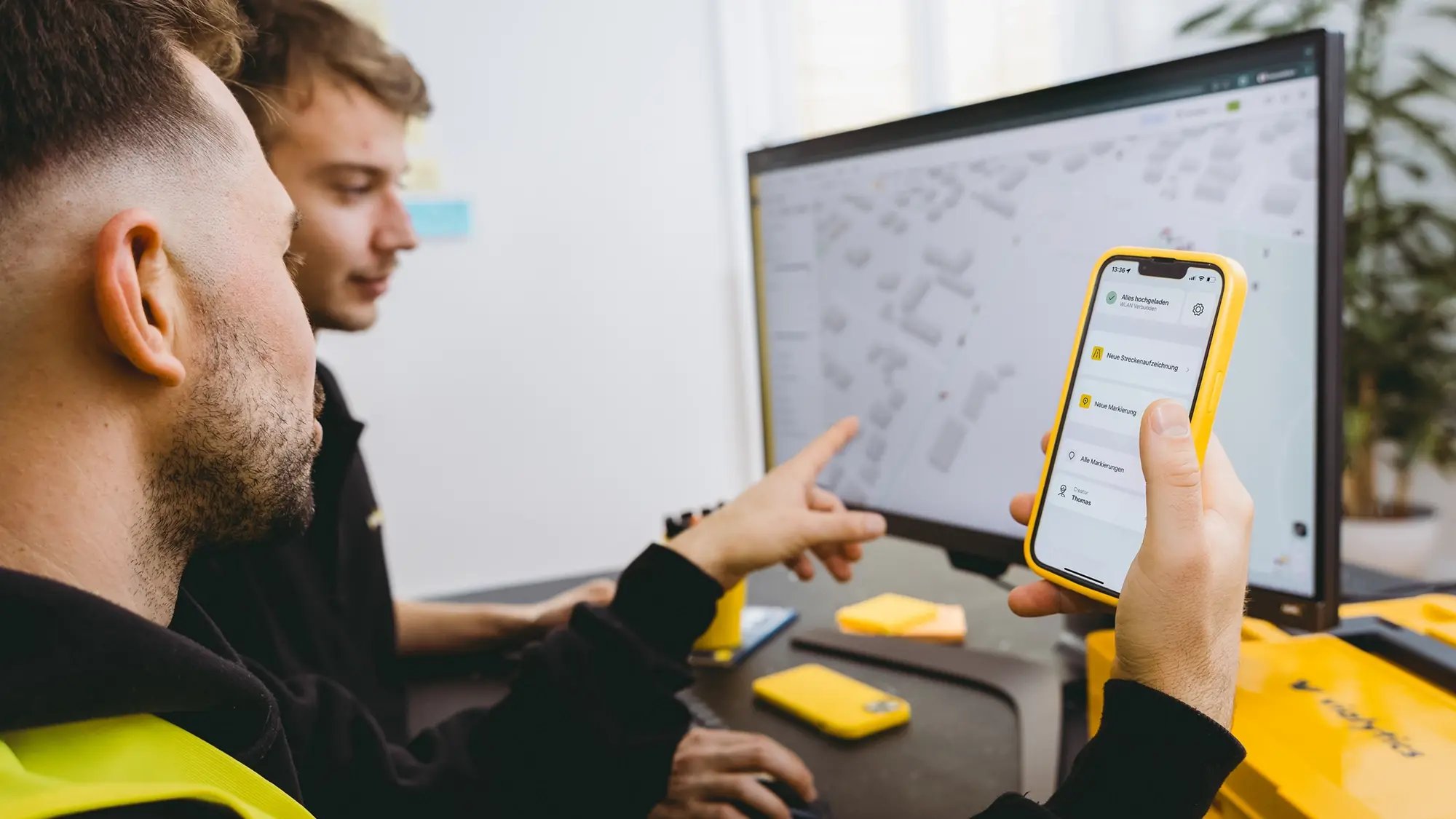 Zwei Mitarbeitende prüfen und bearbeiten Gewährleistungsfälle gemeinsam am PC und Smartphone.