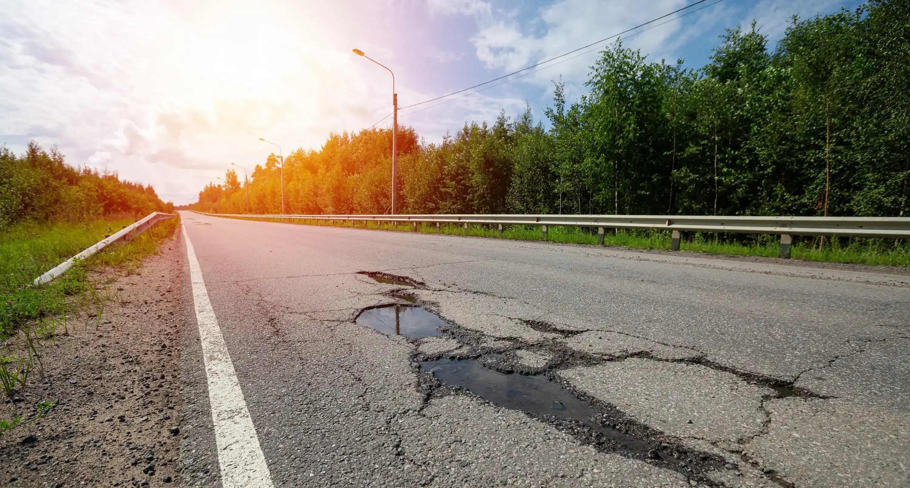 Nahaufnahme von Rissen auf einer Straßen im Sonnenlicht