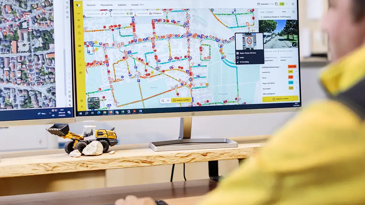 Bauamtsmitarbeiter sitzt vor 2 Monitoren und bedient das vialytics Web System