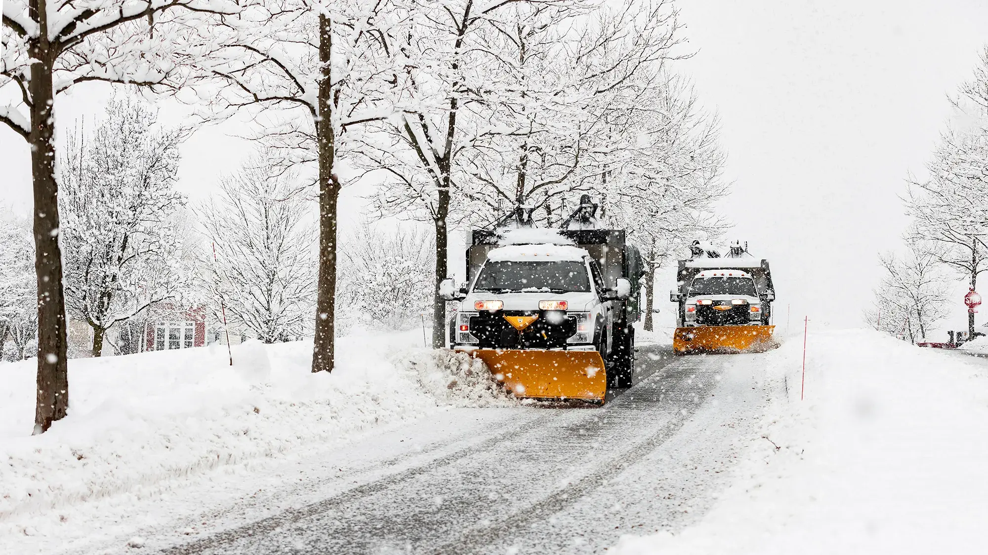 Zwei Räumfahrzeuge im Einsatz auf einer verschneiten Straße