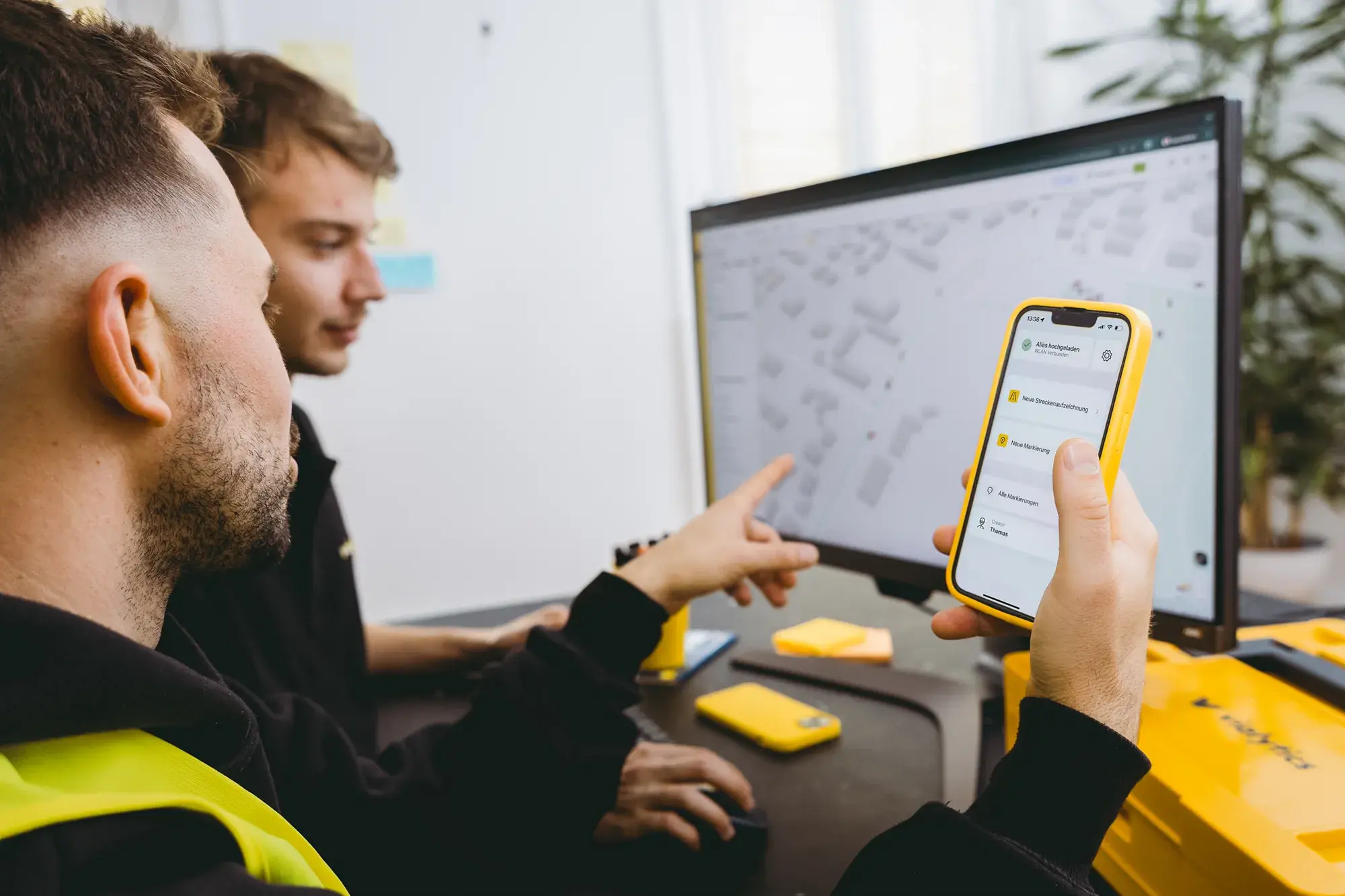 Zwei Personen vor einem PC mit dem vialytics Web-System. Eine Person nutzt parallel die vialytics App.